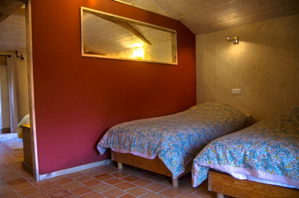 Chambre d'hôte à La Perdrière, Bournezeau, avec un grand lit 160x200 et un espace enfant séparé avec 2 lits 90x200. Chambre de charme, à la ferme, avec charpente apparente, sol en tomettes et décoration moderne.