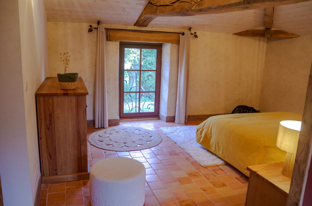 Chambre d'hôte à La Perdrière, Bournezeau, avec un grand lit 160x200 et une vue sur la campagne environnante. Chambre de charme, à la ferme, avec charpente apparente, sol en tomettes et décoration moderne.