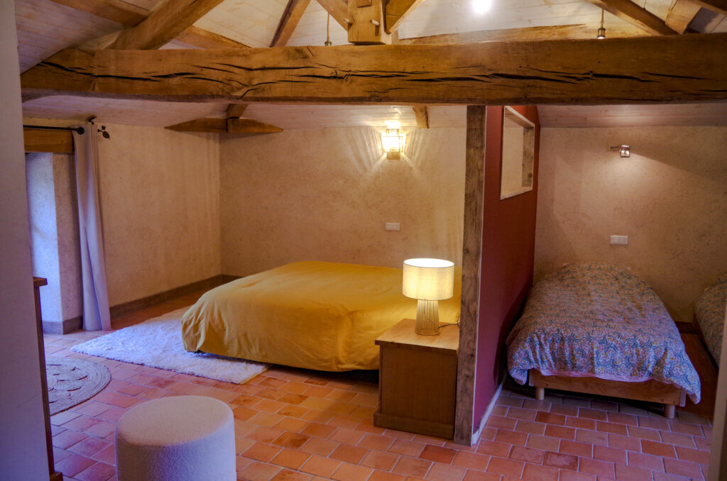 Chambre d'hôte à La Perdrière, Bournezeau, avec un grand lit 160x200 et un espace enfant séparé avec 2 lits 90x200. Chambre de charme, à la ferme, avec charpente apparente, sol en tomettes et décoration moderne.